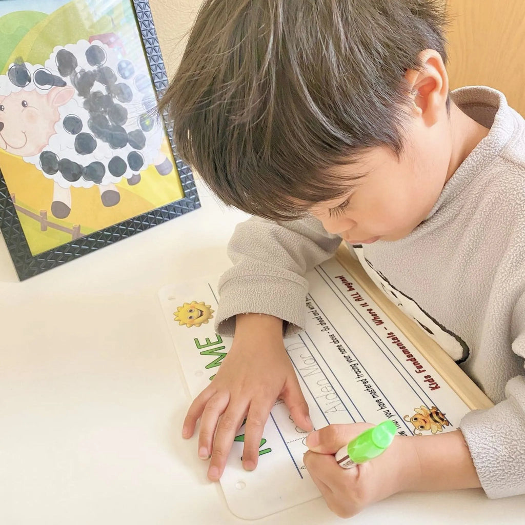 Preschool aged boy actively practicing writing his name on the Learn To Write My Name Handwriting Board